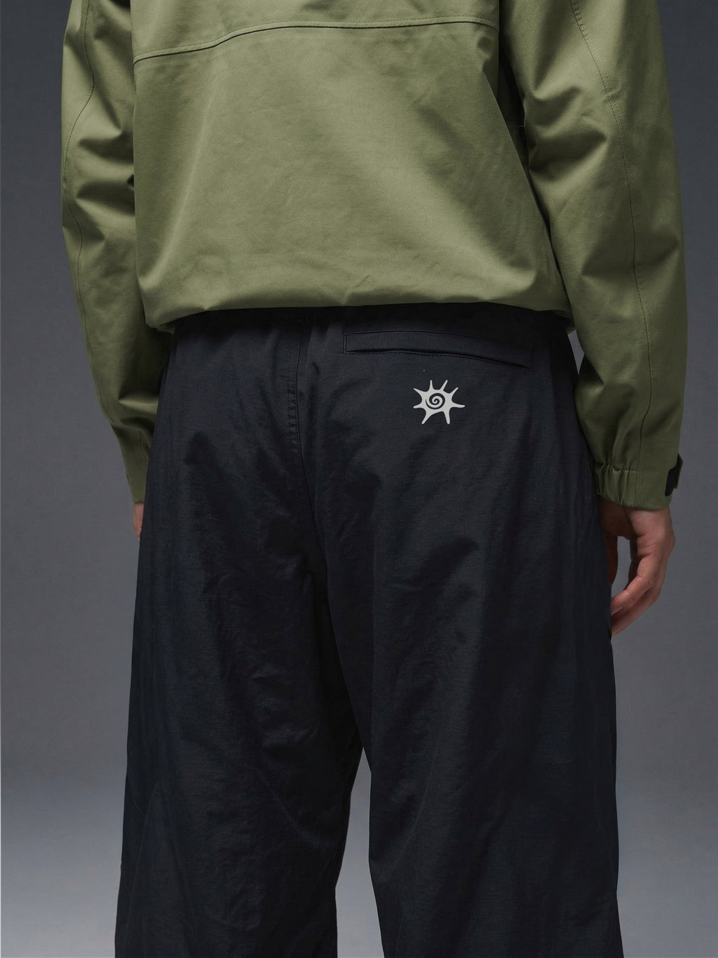 Detalle de la cintura elasticada y cinturón integrado del pantalón técnico SOLAN Trek para un ajuste personalizado en montaña. Logo reflectante SOLAN en pantalón técnico, diseñado para visibilidad y seguridad en trekking nocturno.