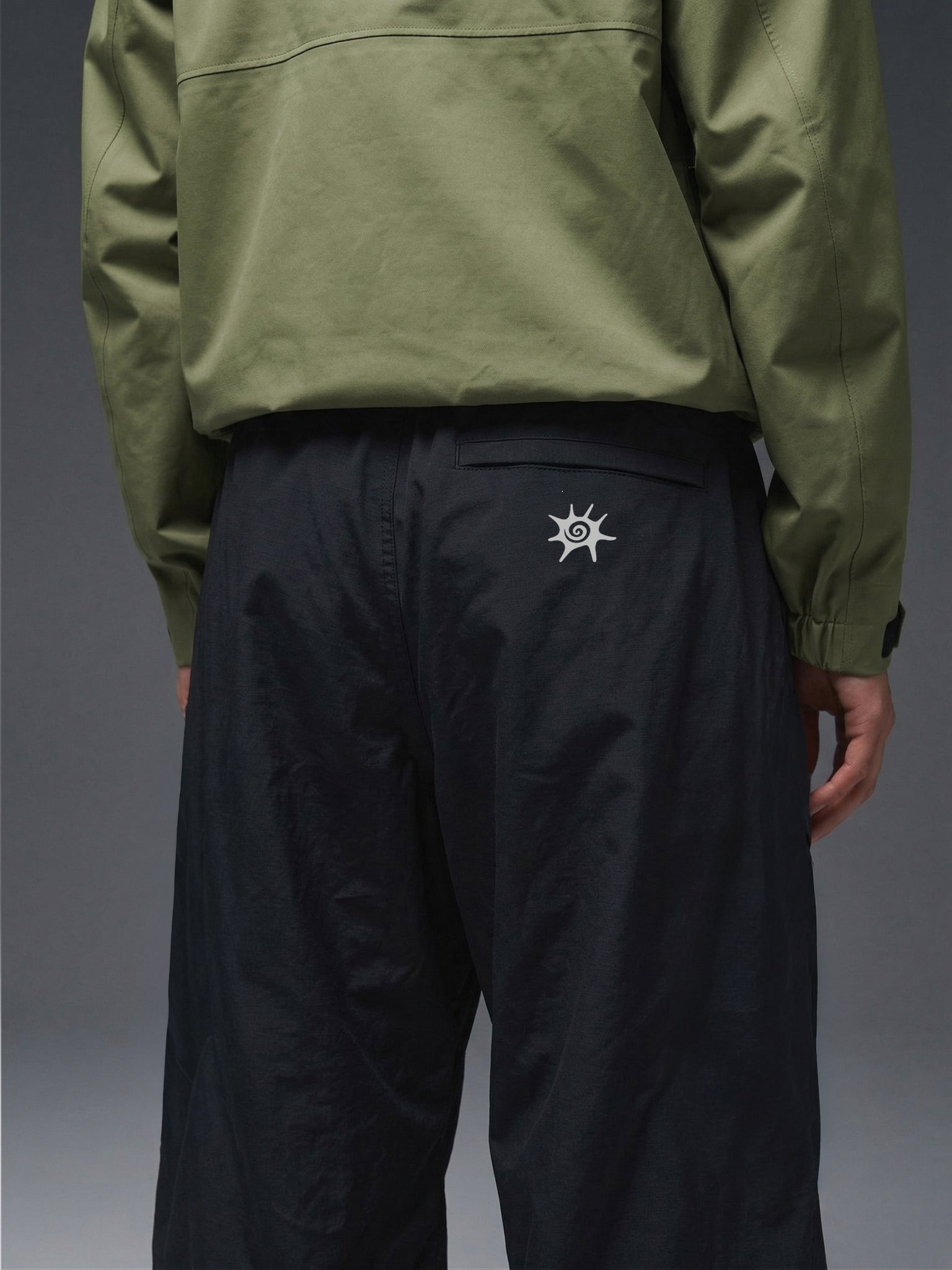 Detalle de la cintura elasticada y cinturón integrado del pantalón técnico SOLAN Trek para un ajuste personalizado en montaña. Logo reflectante SOLAN en pantalón técnico, diseñado para visibilidad y seguridad en trekking nocturno.